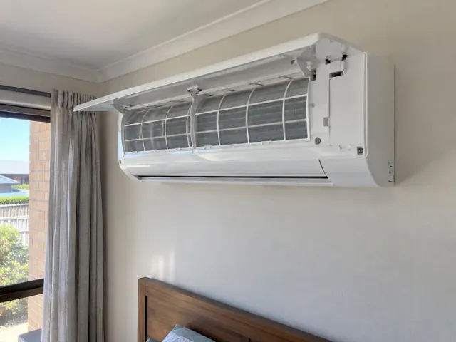 Clean split system with open front panel and visible filters on a bedroom wall in Blakeview